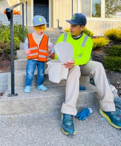 Image: Garbage Collector sits on steps with child dressed as a collector for Halloween
