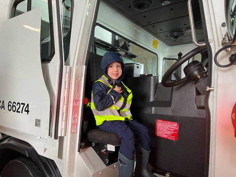 Little boy sits in garbage truck.