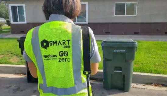 A Race to Zero Waste employee stands in front of carts during a route review
