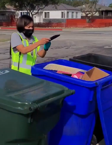 A Race to Zero Waste Auditor takes a picture of an open recycling cart