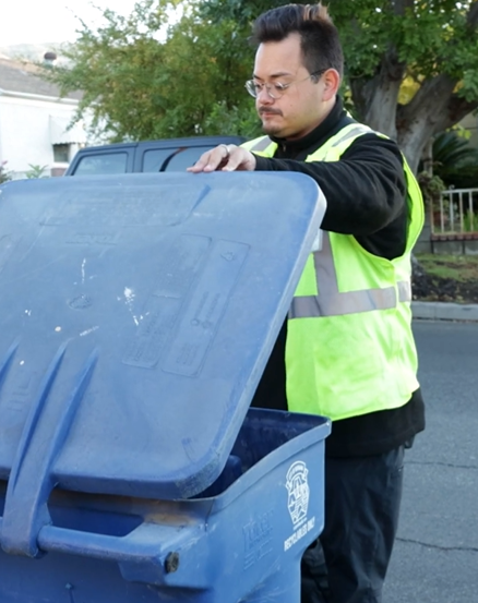 A Race to Zero Waste Auditor lifts a cart lid for inspection